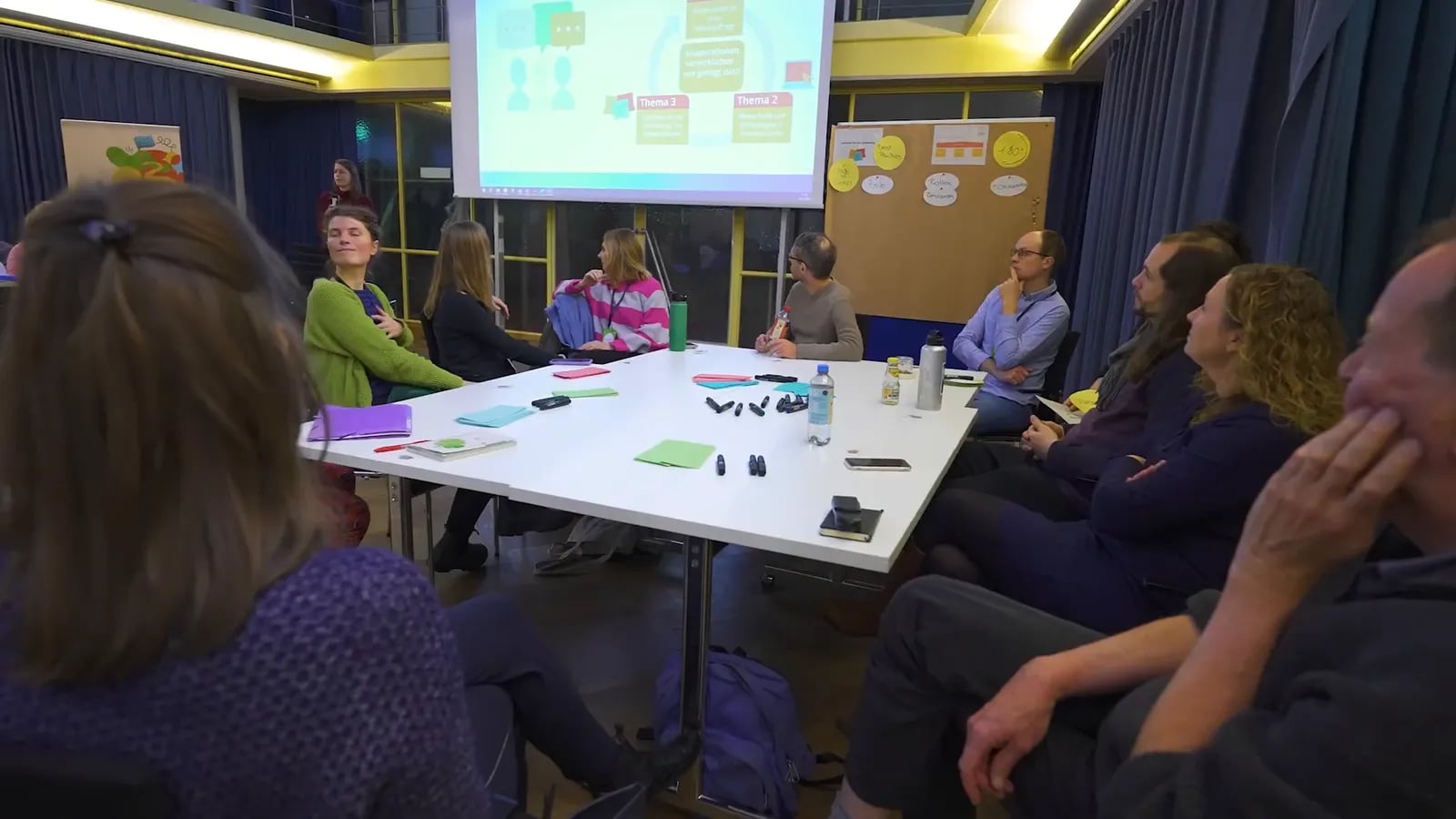 Workshop im Saal: Teilnehmende an Tischen, vorn eine Leinwand
