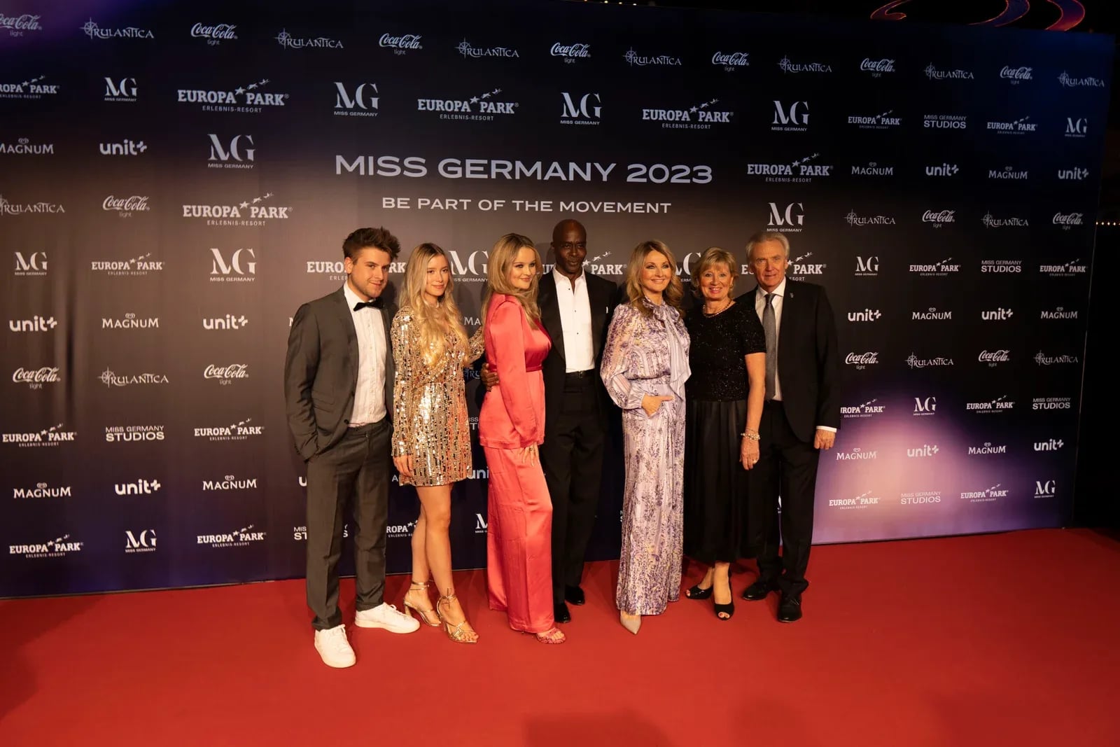 Sieben Gäste vor der Sponsorenwand von Miss Germany 2023 auf dem roten Teppich