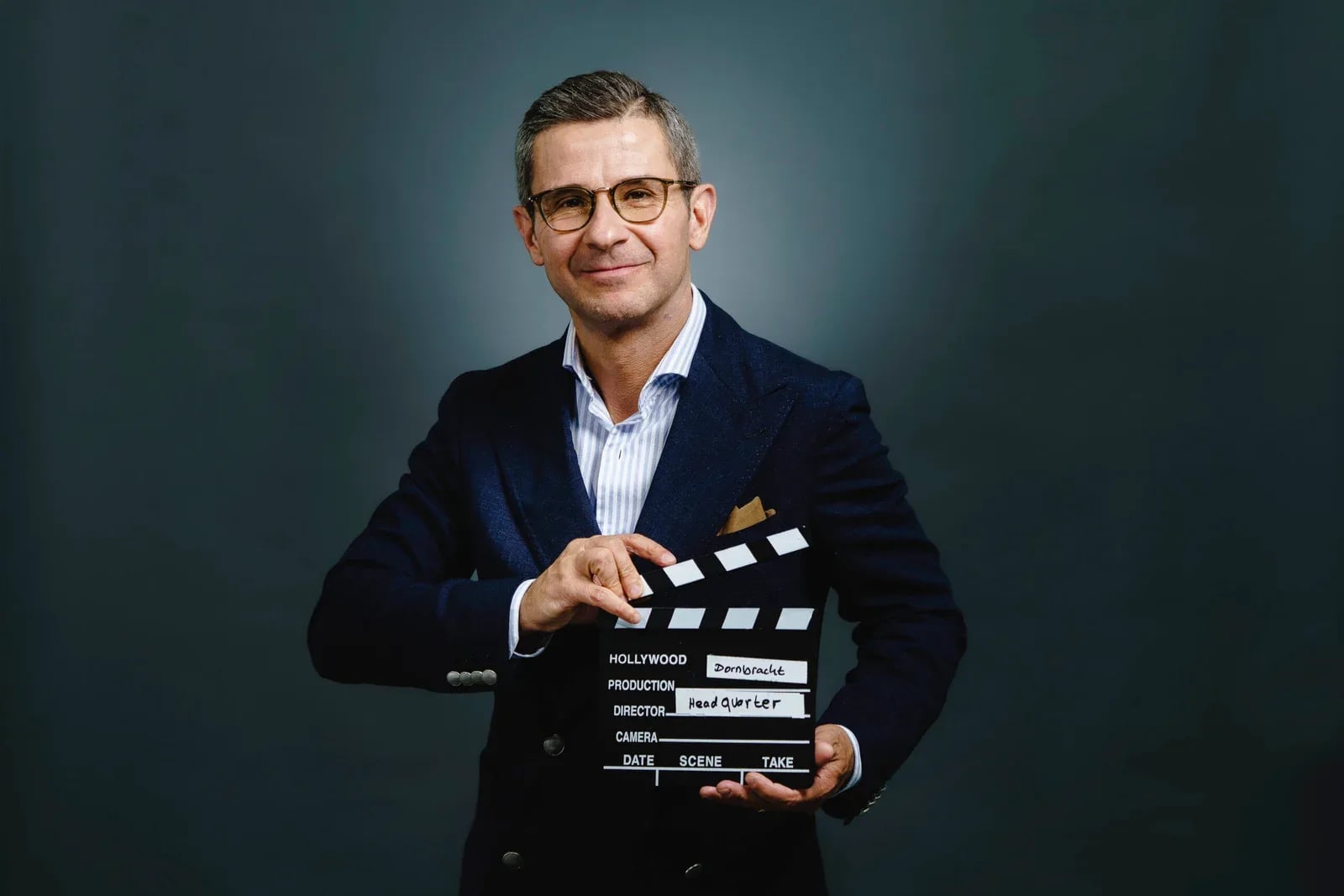 Mitarbeiter im dunkelblauen Sakko schlägt die Filmklappe