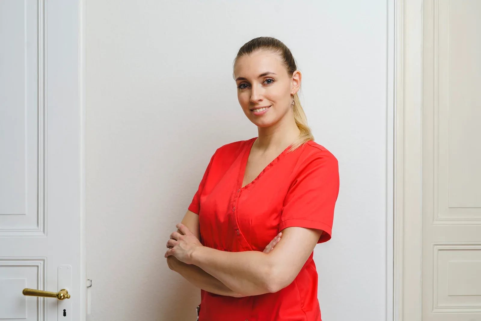 Porträt einer Assistentin mit verschränkten Armen vor einer Altbautür