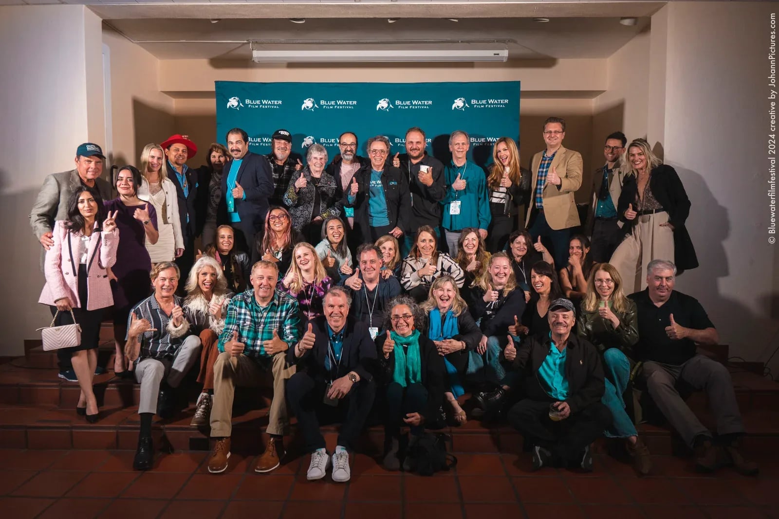 Gruppenbild der Filmschaffenden und Gäste auf einer Treppe vor der Festivalwand