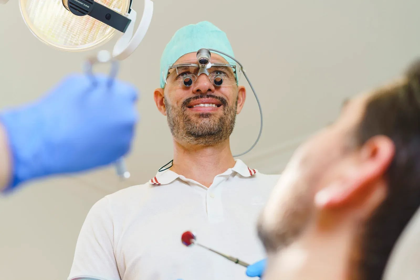 Zahnarzt mit Lupenbrille und Stirnlampe, von unten aus Sicht des Patienten